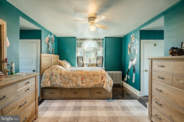 bedroom with ceiling fan, radiator heating unit, and wood-type flooring