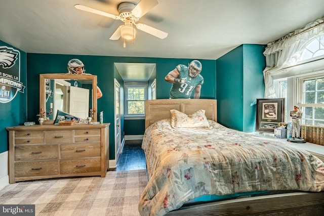 bedroom featuring ceiling fan, multiple windows, and light hardwood / wood-style floors