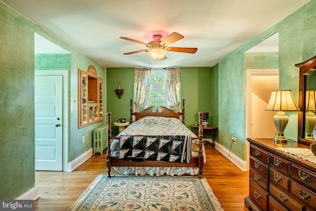 bedroom with light wood-type flooring, radiator heating unit, and ceiling fan