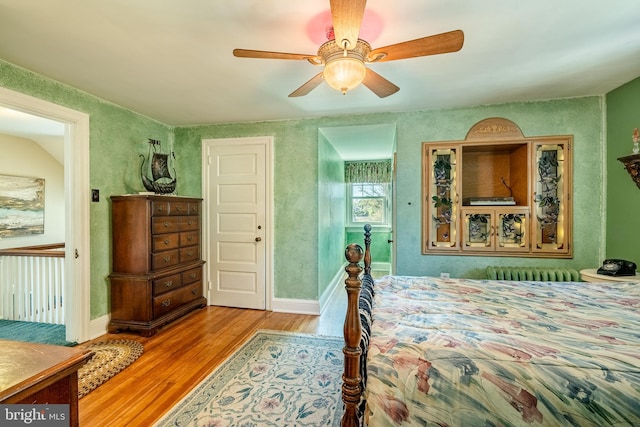 bedroom featuring radiator, hardwood / wood-style floors, and ceiling fan