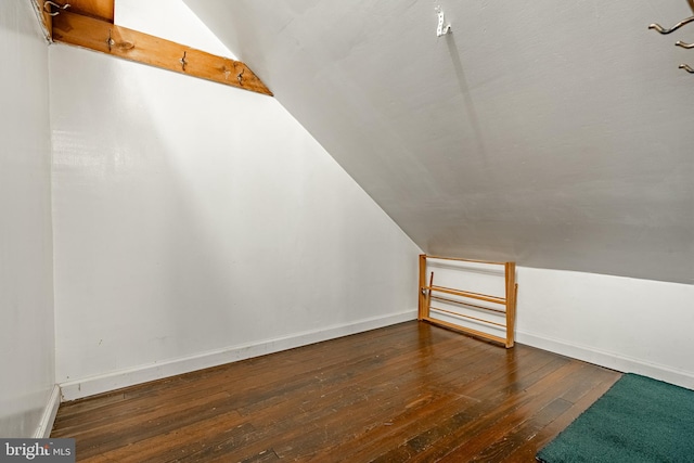 additional living space featuring dark wood-type flooring and lofted ceiling