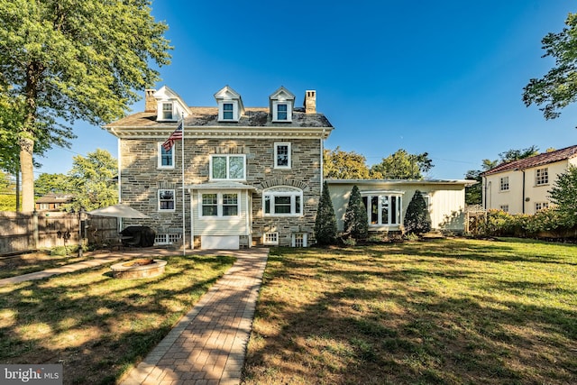 back of house with a lawn and an outdoor fire pit