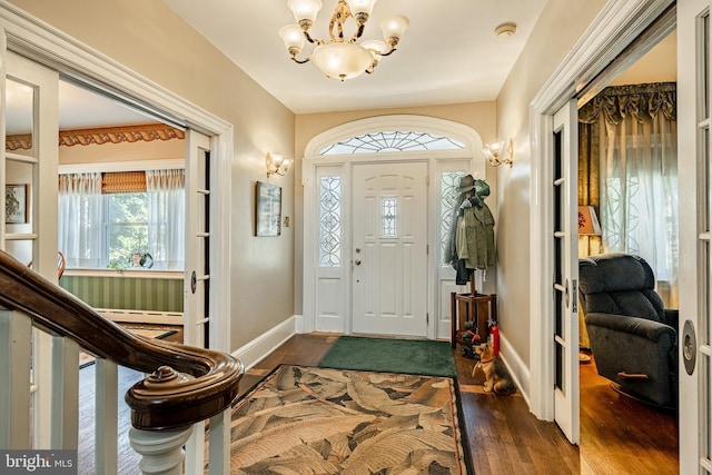 entrance foyer featuring dark wood-type flooring, an inviting chandelier, and a baseboard radiator