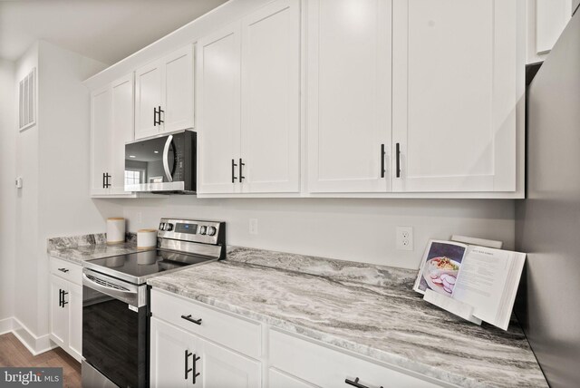 kitchen featuring light stone counters, white cabinets, appliances with stainless steel finishes, and dark wood-type flooring