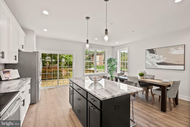 kitchen featuring hanging light fixtures, a center island, light hardwood / wood-style flooring, and white cabinets