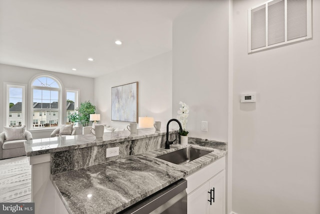 kitchen featuring stone countertops, sink, and white cabinetry