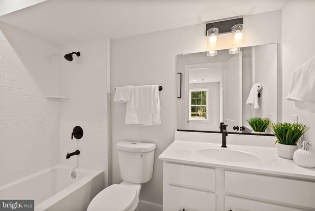 full bathroom featuring vanity, tiled shower / bath combo, and toilet