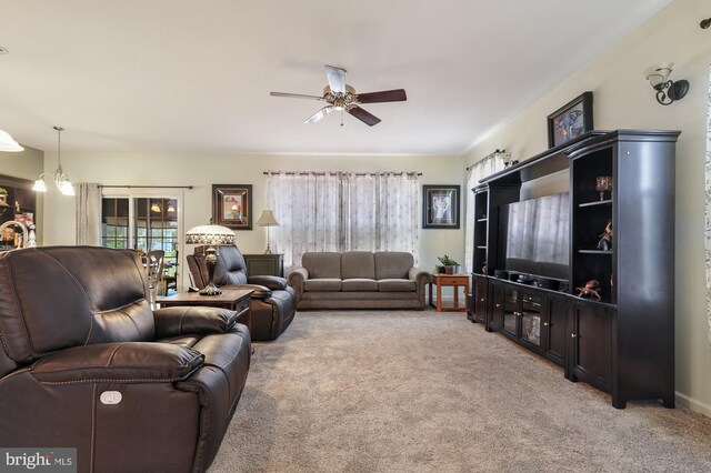 living room featuring light carpet and ceiling fan with notable chandelier