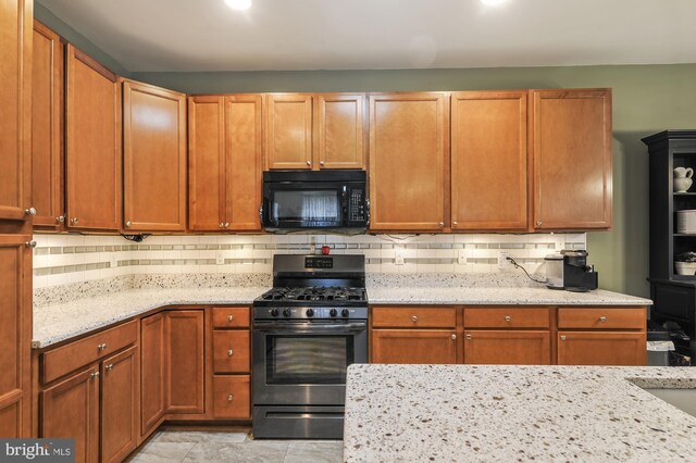 kitchen with light stone countertops, hanging light fixtures, and black appliances