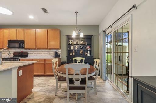 kitchen with black appliances, decorative light fixtures, a chandelier, and tasteful backsplash