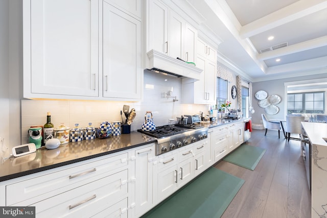 kitchen featuring stainless steel gas stovetop, backsplash, white cabinets, dark hardwood / wood-style floors, and ornamental molding