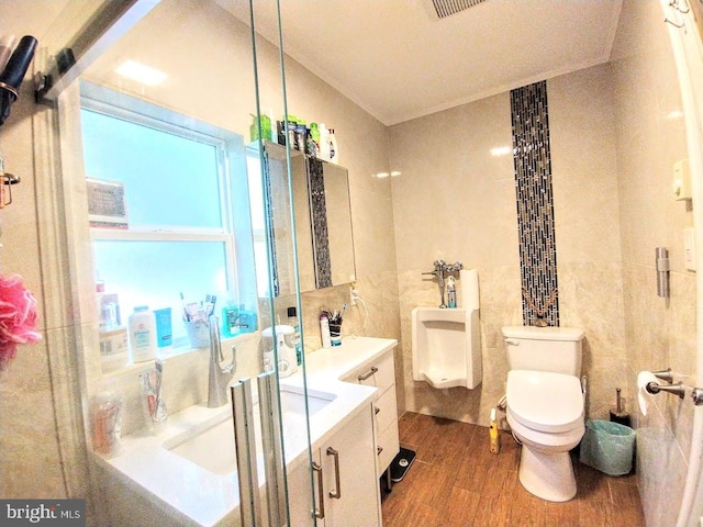 bathroom with hardwood / wood-style flooring, walk in shower, toilet, tile walls, and vanity