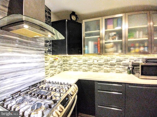 kitchen with backsplash, wall chimney exhaust hood, and stainless steel gas range oven