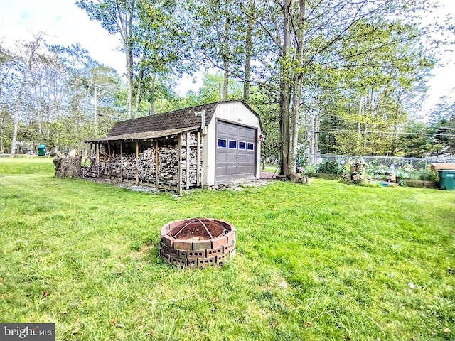 view of yard featuring an outdoor fire pit, a garage, and an outdoor structure