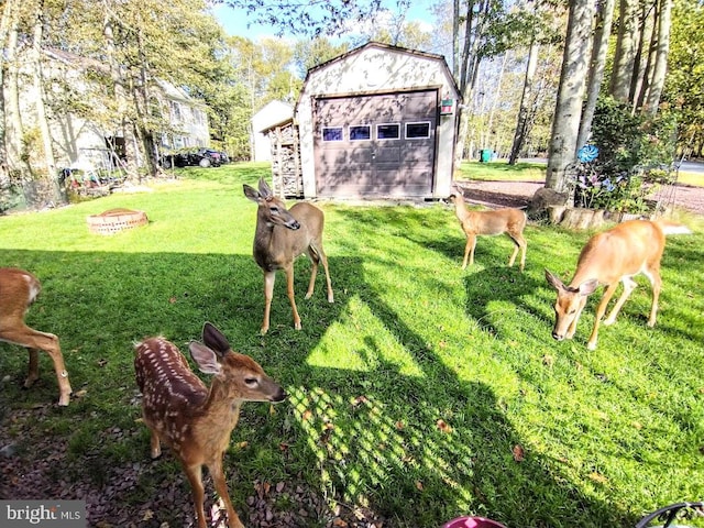 view of yard featuring a garage, an outbuilding, and an outdoor fire pit