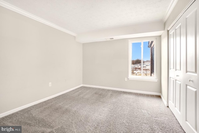 empty room with crown molding, a textured ceiling, and carpet