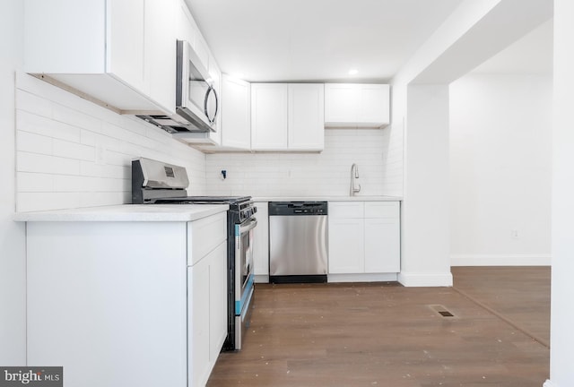 kitchen featuring visible vents, appliances with stainless steel finishes, wood finished floors, white cabinets, and a sink