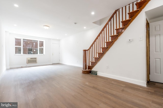 unfurnished living room with recessed lighting, baseboards, a wall unit AC, and wood finished floors