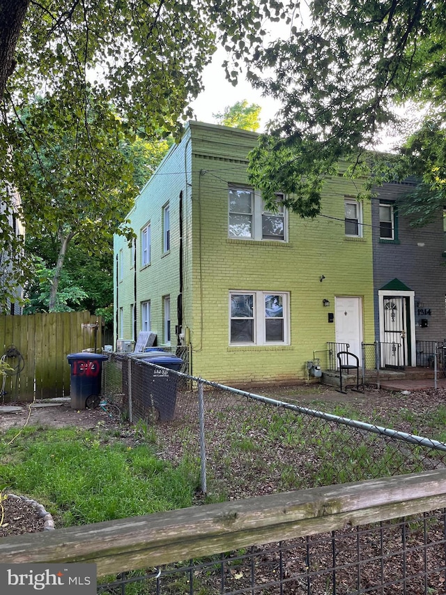 view of front of house featuring brick siding and fence