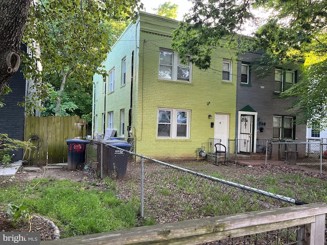 view of front of house featuring a fenced backyard, brick siding, and central AC