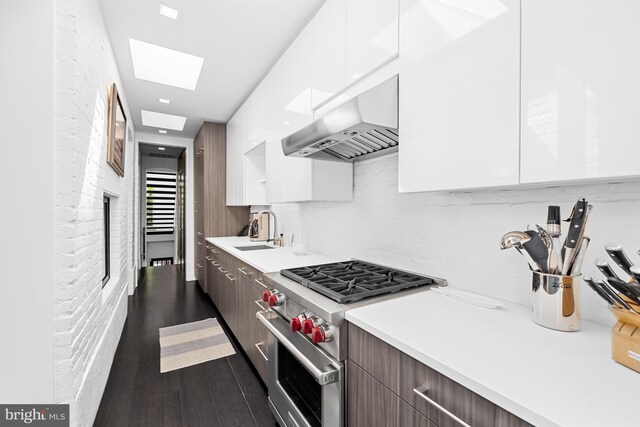 kitchen with designer range, exhaust hood, dark hardwood / wood-style flooring, sink, and white cabinets