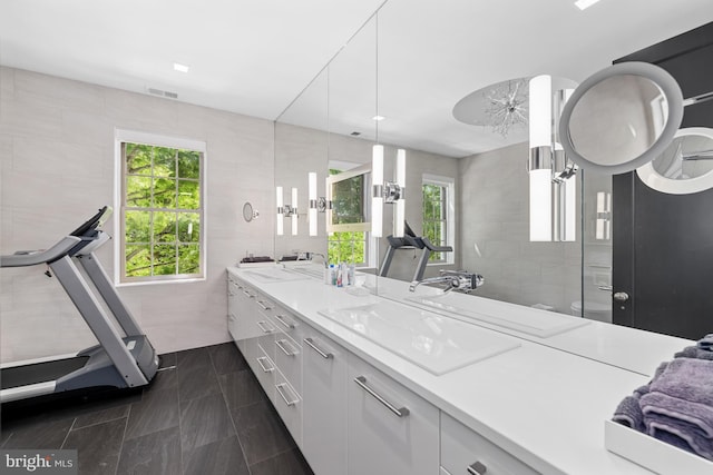 bathroom with visible vents, a ceiling fan, a sink, tile walls, and double vanity