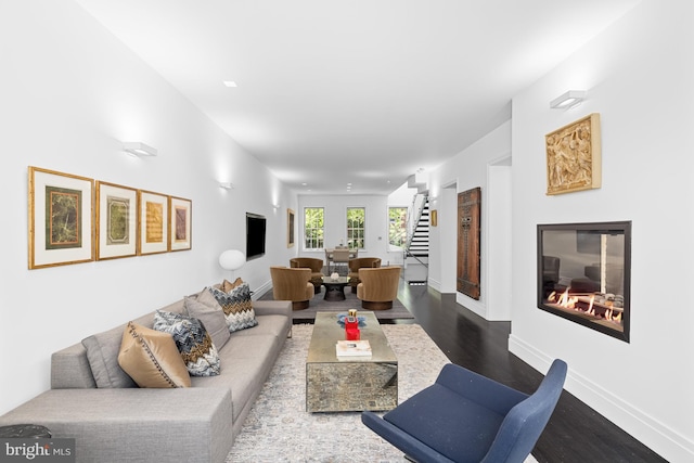 living area featuring stairs, dark wood-style floors, and baseboards