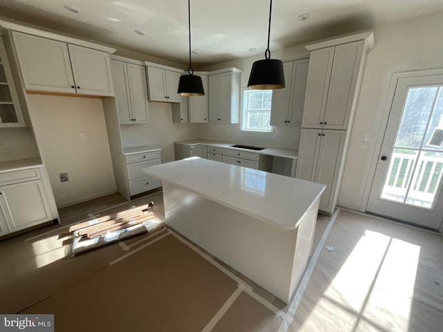 kitchen featuring decorative light fixtures, a center island, light wood-type flooring, and white cabinetry