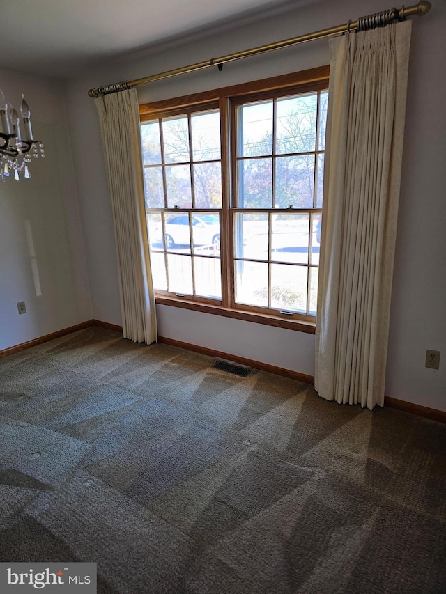 carpeted empty room with a chandelier and a healthy amount of sunlight