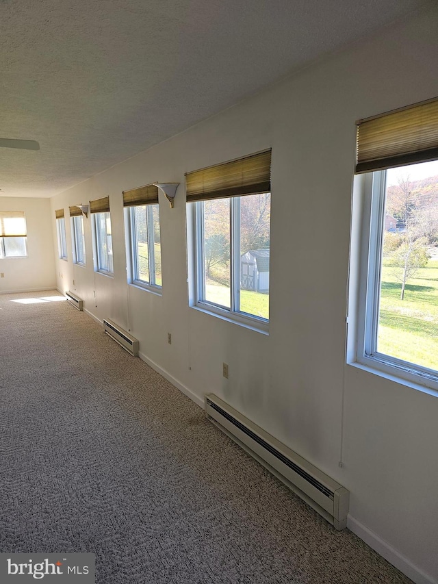 spare room with carpet and a baseboard heating unit