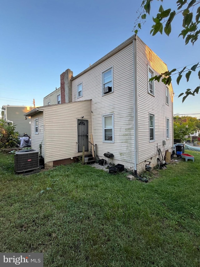 back of house featuring a lawn and central AC