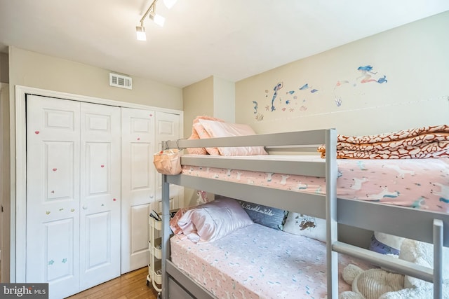 bedroom featuring a closet, hardwood / wood-style floors, and rail lighting