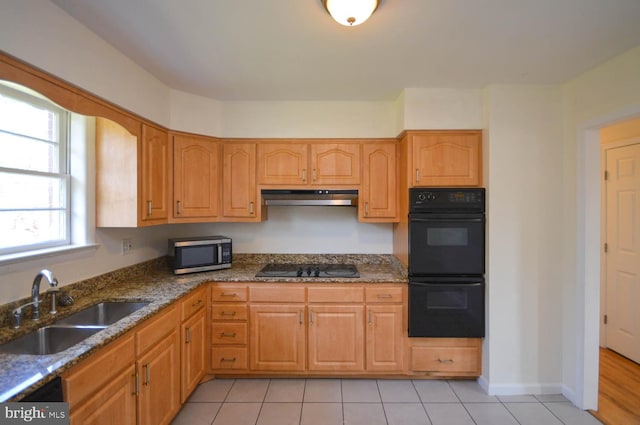 kitchen featuring black appliances, dark stone countertops, light tile patterned flooring, and sink