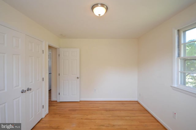 unfurnished bedroom with light wood-type flooring and a closet