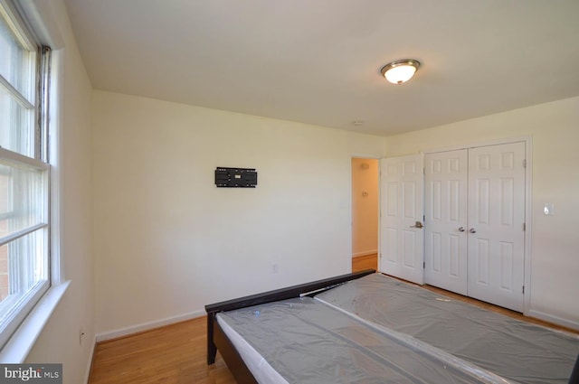 unfurnished bedroom featuring multiple windows, hardwood / wood-style flooring, and a closet