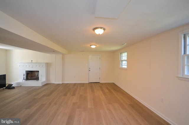 unfurnished living room with light hardwood / wood-style floors and a brick fireplace