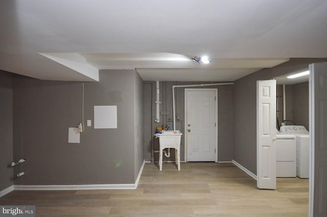 basement featuring light hardwood / wood-style flooring, sink, and separate washer and dryer