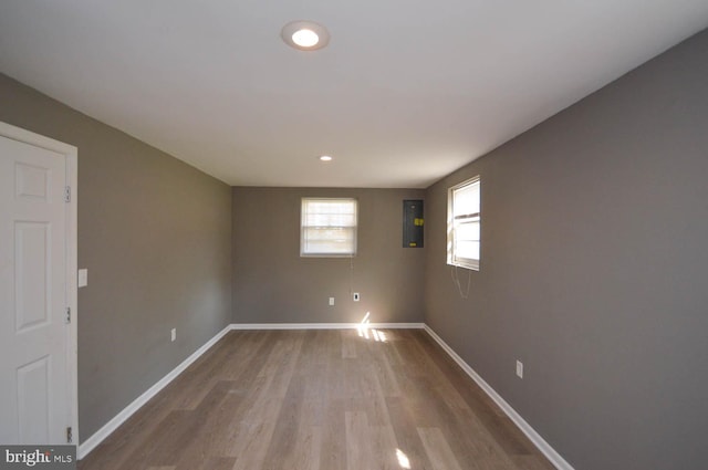 spare room featuring electric panel and light wood-type flooring