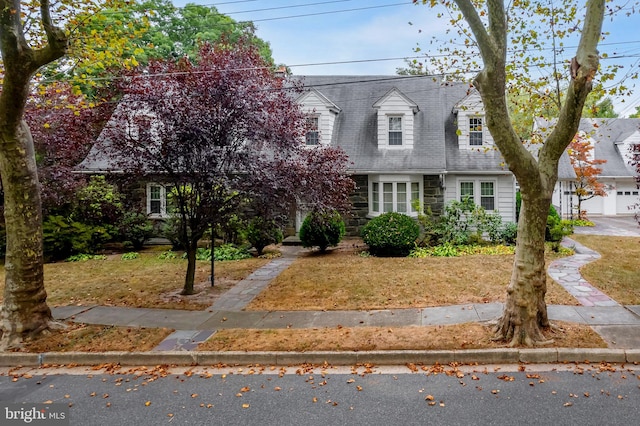 new england style home featuring a front yard and a garage