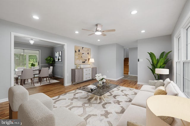 living room with light wood-type flooring, ornamental molding, and ceiling fan