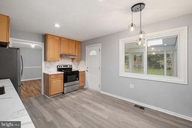 kitchen featuring light hardwood / wood-style floors, light stone counters, tasteful backsplash, pendant lighting, and stainless steel appliances