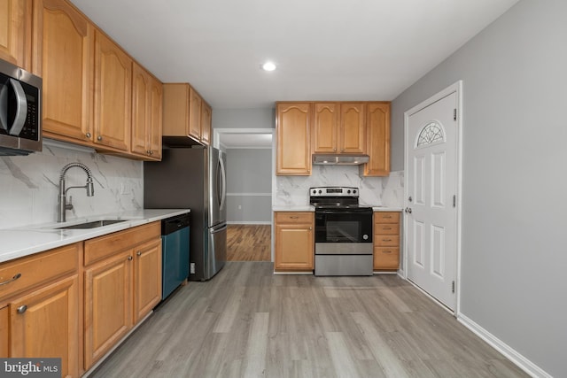 kitchen with stainless steel appliances, sink, tasteful backsplash, and light hardwood / wood-style flooring