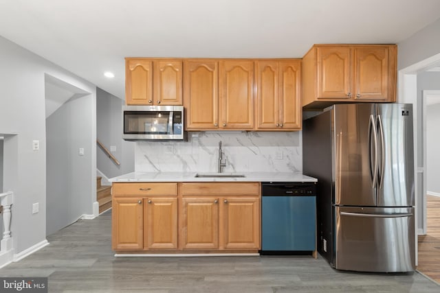 kitchen featuring appliances with stainless steel finishes, decorative backsplash, light hardwood / wood-style floors, and sink