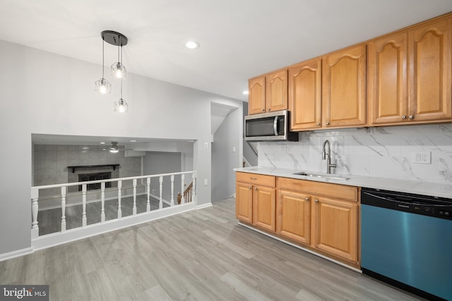 kitchen with pendant lighting, tasteful backsplash, sink, light hardwood / wood-style flooring, and appliances with stainless steel finishes