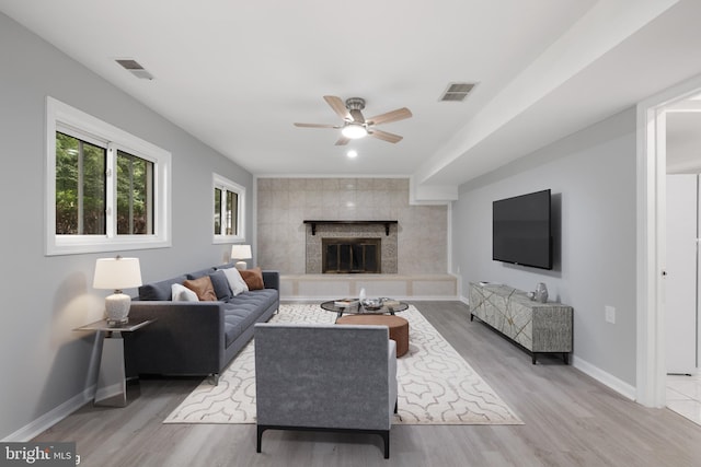 living room featuring a tiled fireplace, ceiling fan, and hardwood / wood-style flooring