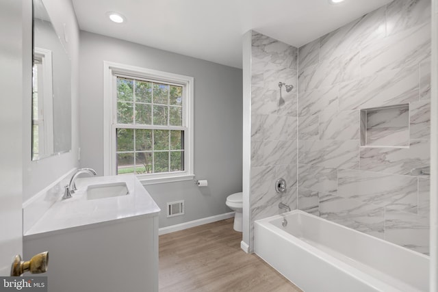 full bathroom featuring vanity, tiled shower / bath combo, toilet, and hardwood / wood-style flooring