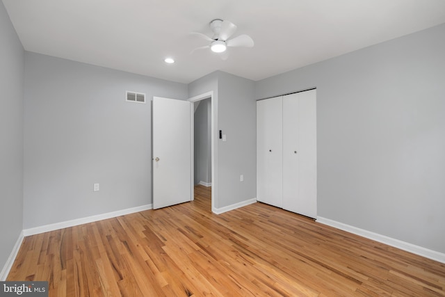 unfurnished bedroom with light wood-type flooring, ceiling fan, and a closet