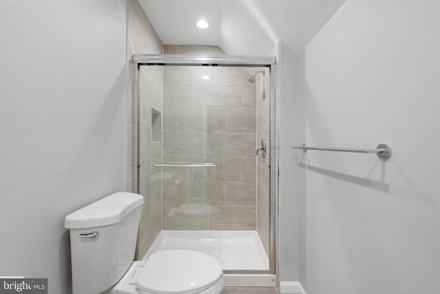 bathroom featuring vaulted ceiling, a shower with door, and toilet