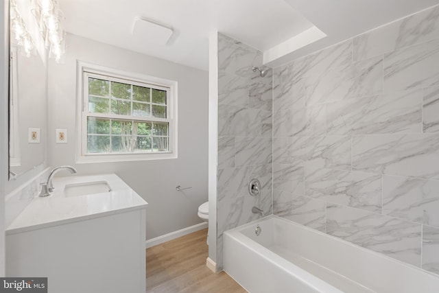 full bathroom with wood-type flooring, tiled shower / bath combo, vanity, and toilet