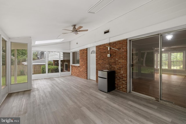 unfurnished sunroom featuring ceiling fan and a skylight